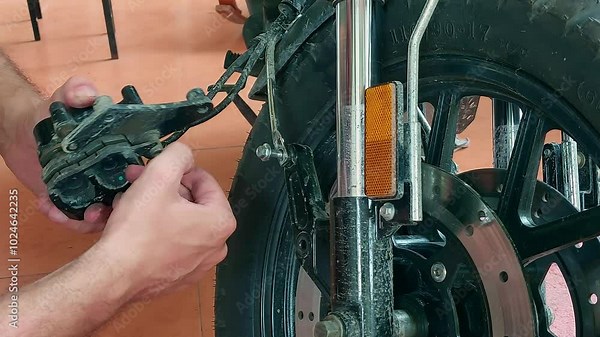 Examining and checking the front brake system of a motorcycle showing DIY vehicle home maintenance