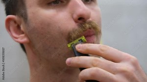 The man shaves his big beard. The guy shaves off his big beard. Young guy shaves his beard at home. Personal care Stock Video