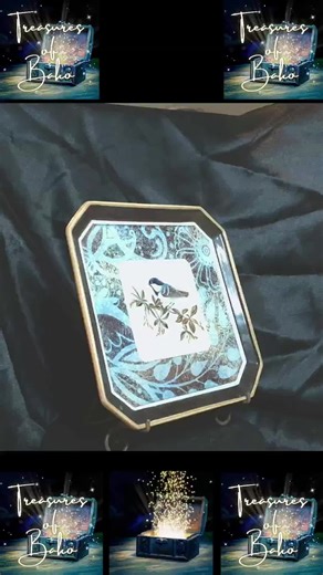 Some pieces of décor don’t need bright colors or bold patterns to stand out—they speak in softer tones, the way nature often does. This Grasslands Road decorative plate captures that feeling beautifully. At the center, a small chickadee rests on a branch, painted with delicate detail and soft shading. Its feathers, tiny beak, and curious eye feel almost lifelike, as though the bird paused just long enough for nature to become art. Surrounding it is a layered background of warm browns, muted blue