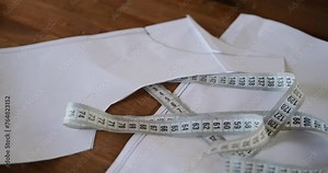 Background video top-down view of a tailor work table on which lies a measuring tape, a pattern on paper, chalk, and thread. Fashion designer workspace, creation process.