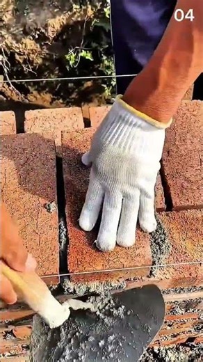 String line guides the lay—red bricks stack tight as wall rises over green earth