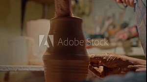 Pottery workshop. Old man potter professionally creates perfect form and shape for mug when it spinning on work table. Close up artisan shaping clay sculpture in home studio