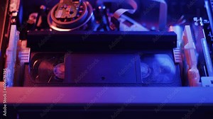 A wide shot of a VHS tape inserted into a VCR. The tape is played and fast forwarded at different speeds.