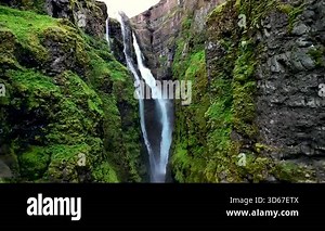 Experience the breathtaking beauty of Glymur waterfall, Icelands tallest waterfall, cascading down rocky cliffs into a serene river.