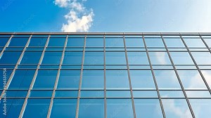 the glass facade of a modern building, featuring a sleek design with repeating windows and a structured metal framework, capturing the contemporary architecture and symmetry of the urban landscape