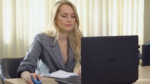 Young business woman in suit works with documents at the computer in office