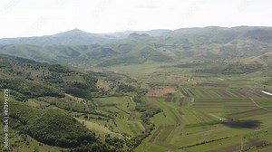 Slow aerial panning view over fertile valley farmland near Piatra Secuiului, villages of Rimetea and Coltesti, Romania
