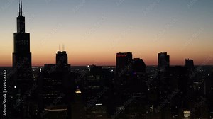 Chicago aerial view of city skyline silhouette flying at building level along the waterfront. Featuring Willis Tower, Aon Center and Crain Communications Building