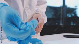 Woman doctor putting blue latex medical gloves on white background.Surgeon wearing gloves before surgery at operating room.Risk and infection control concept.