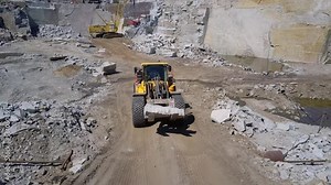 Heavy Loader Machinery Transports Piece Of Natural Granite Stone. Heavy Loader Machinery At An Industrial Quarry Site. Heavy Loader Machinery Driving Through Mineral Quarrying Site. Natural Resources