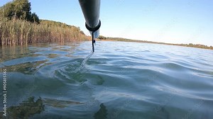 Paddle rowing calm surface of water - horizontal first-person video