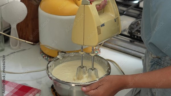 Woman Hands Whipping Cream For Tiramisu Cake Using Electric Hand Mixer On The Kitchen Table