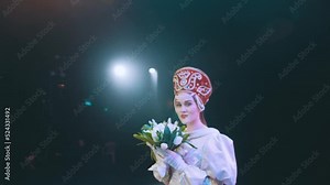 A theater actress with flowers in her hands in a bride’s dress on stage. opera. performance. the tsar’s bride.
