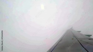 Canted angle shot over wing of airplane as it exits the cloud cover over Montreal, Canada.