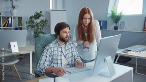 Close up young guy and woman talking smiling using computer and headphones. Young people are working in coworking space offices. Sunlight. Call centre. Slow motion