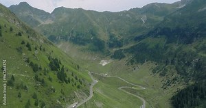 Aeriel Drone View of the Transfagarasan Highway in the Carpathian Mountains of Transylvania in summer with green forest and grass. Winding Road with cars driving in 4K