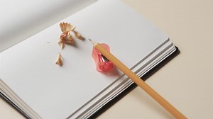 Close up of open notebook with pencil and pencil sharpener on beige background, in slow motion Premium Stock Video Footage