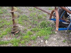 Post hole digger in ground operation on rocky soil