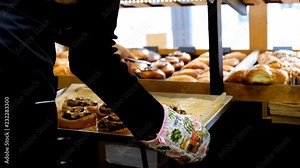 the pastry chef lays out fresh pastries on the storefront in the bakery.