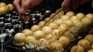 Slow Motion Japanese vendor prepare a Takoyaki on hot pan food Japan. Process to cooking the popular fried balls with octopus in local street food. Making a Ball-shaped food at asia night market.-Dan