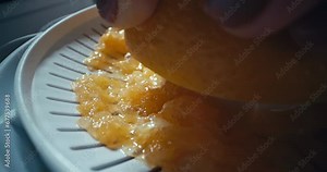 Macro slow-motion video of squeezing juice from an orange with a juicer. Fresh citrus juice at home in the kitchen for breakfast. High quality 4k footage