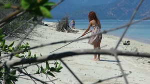 Girl on a beach writing and drawing in sand