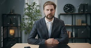 Bearded businessman in formal wear sitting at modern office, smiling and looking at camera. Happy mature man spending day at workplace.