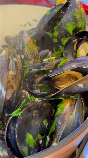 Cooking mussels with white wine and garnishing with parsley.