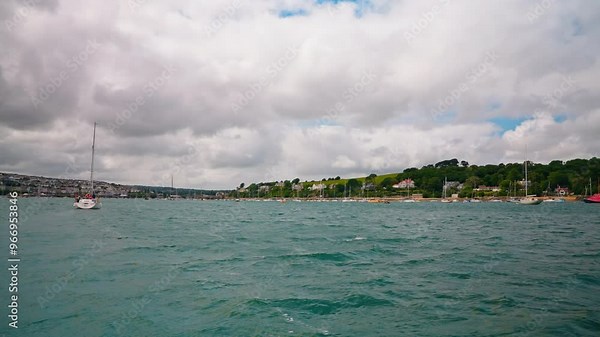 Boat tour on Fal River in Cornwall, United Kingdom, discovering the nearby towns in the region. View of Falmouth town and the sailing boats in the distance.