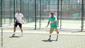 Two adult athletic men playing doubles padel tennis on court