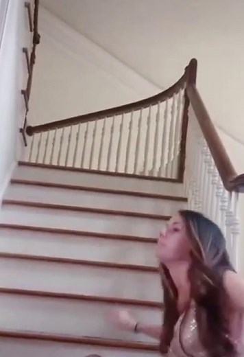Girl walking down stairs with new dress then trips and falls.