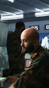 Vertical video Man looking at screens in military HQ base housing operational missile defense system designed to intercept ballistic rockets. Special forces expert using tracking gear and radar