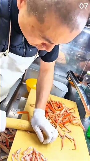 Cracking crab legs using rolling pin on yellow board