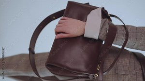 Elegant handbag in a woman's hand, a girl with a beautiful handbag, a girl model posing with a handbag, a woman's bag, shooting in slow motion, vertical shooting