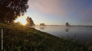 Zeitraffer am See mit Baum auf Insel im Nebel bei Sonnenaufgang