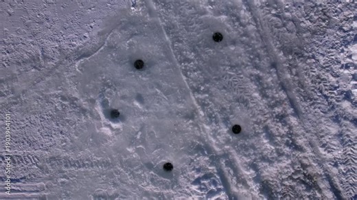 Aerial view of the ice fishing holes in the ice with surrounded snowmobile atv or snowdog tracks across frozen lake of Simcoe lake in Cook’s Bay, Innisfil. Ice fishing season for jumbo perch and pike