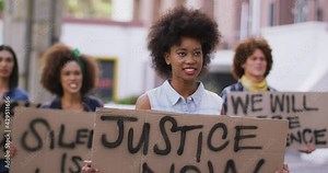 Diverse group of men and women holding placards shouting during protest