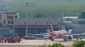 Descargar phuket, tailandia 29 de noviembre de 2019 - avión airasia estacionado en la terminal del aeropuerto de phuket. camiones de bomberos en el aeródromo. concepto de seguridad de aviación