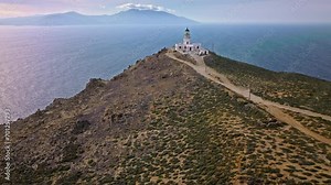 Aerial view of Armenistis lighthouse, a Historical landmark representing maritime history in Mykonos. Lighthouse atop a steep hill offering picturesque views of sea, and sunsets in Greece.