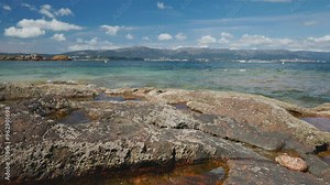 A beautiful Galician beach with rocky shores stretching into crystal-clear waters under a bright sky. Rias baixas, Galicia, Spain. Slider shot