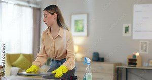 Woman, cleaning and organize desk with service, housekeeping and disinfecting furniture with chemical detergent. Cleaner, hygiene and rearrange office supplies, house work with spray and maintenance