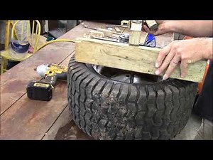 Lawn tractor tire change on a home made tire station, bead breaker