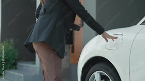 Progressive woman installs a charging station plug into her electric vehicle at home. EV automobiles provide an environmentally beneficial concept of clean and green energy.