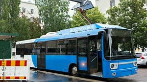 Electric bus at a stop is charged by pantograph. It's lights flash. Camera zoom moves to object. 4k video