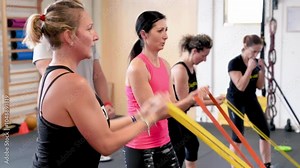 Four women doing trx at the gym, elastic training for biceps