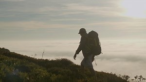 Free stock video - Senior hiker standing on the top of the mountain at sunset and enjoying the landscape