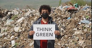 volunteer wearing a mask on disposal site holding agitation slogan. ecological movement activist fighting for ecology - pollution, ecology concept closeup 4k