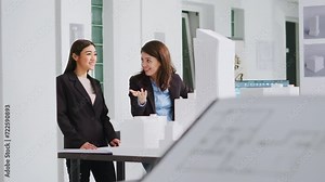 Architects doing high five gesture after finishing blueprints, feeling happy about translating measurements and determining scale elements for building development. Women solve task successfully.