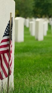 Field of American flags at Sunset. Flags on grave stones for memorial day remembrance at a cemetery. Small American flags and headstones at National cemetary- Memorial Day display.