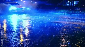 Cars drive into large puddles on the night road in the city, spray puddles scatter from under the wheels of the car